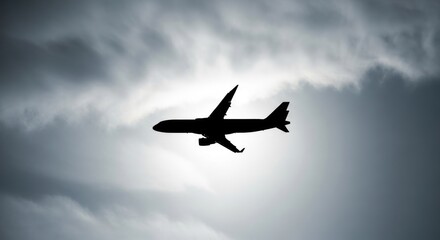 Obraz premium Dramatic silhouette of a commercial airplane soaring against a cloudy sky background
