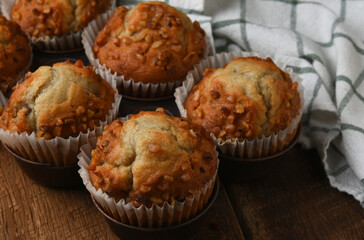 Muffin pan with six fresh baked Banana ut Muffins on a rustic wood kitchen table.