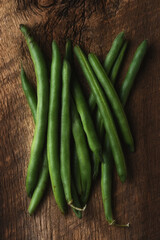 A pile of fresh picked homegrown green beans on a rustic wooden table.