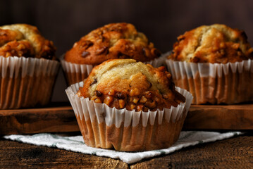 Closeup of a fresh homemade Banana Nut Muffin with three out of foucs muffins behind.