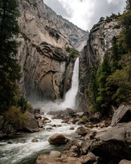Obraz premium Roaring Yosemite Fall Plunges Through a Majestic Granite Canyon Under a Cloudy Sky.