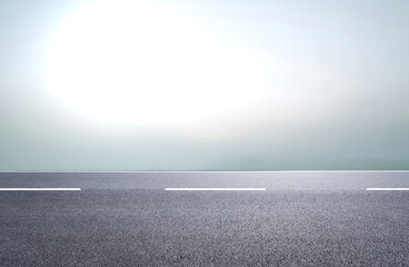 Empty asphalt road with white dashed lines stretching into a bright, hazy, and minimalist sky, offering a sense of open space and journey.