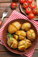 Tasty baked potatoes with rosemary served on wooden table, flat lay