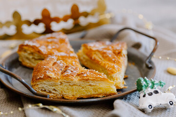 On one plate on the table are three pieces of galette with a crown and garland.