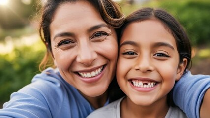 Joyful close-up portrait of a happy Hispanic mother and her young daughter with a missing tooth smiling brightly outdoors in natural sunlight.