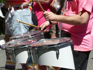 Drummer wearing pink t-shirt playing during pride parade celebrating diversity and inclusion
