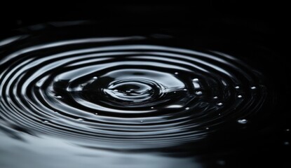 Concentric ripples spreading across dark water surface creating a calming and mesmerizing pattern