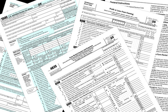 Tax year 2025 IRS 1040 and farming tax forms on a desktop.
