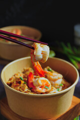 Pad Thai stir-fried with shrimp, eggs, peanuts and lime, served in paper.
