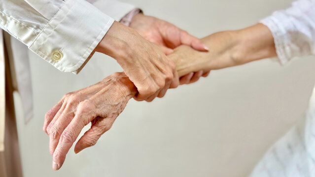 高齢女性の腕をマッサージする女性の手