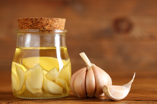 Jar of fresh garlic oil on wooden background