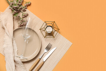 Beautiful table setting with gypsophila flowers and burning candle on orange background