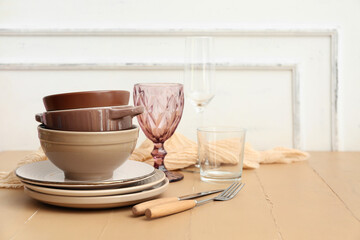 Different clean dishes and cutlery on beige wooden table