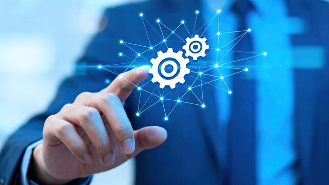 A businessman in a suit interacts with digital gears and connections symbolizing technology and innovation in a professional context.