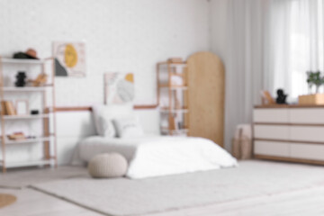 Blurred view of teenager's room with bed, shelf units and paintings