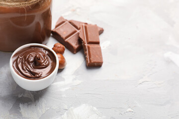 Bowl of tasty chocolate spread with hazelnuts on grunge background