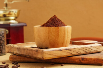 Wooden bowl of coffee powder with beans on beige background
