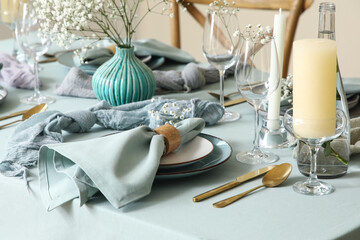 Elegant table setting with golden cutlery, beautiful flowers and candles in restaurant, closeup