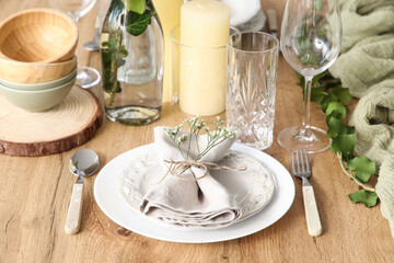 Plate with folded napkin and beautiful flowers on served wooden table in restaurant, closeup