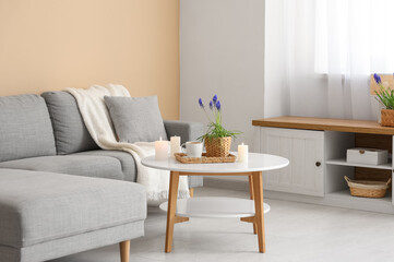 Beautiful Muscari flowers, burning candles and cup of coffee on table in living room