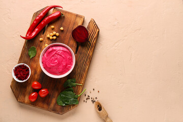 Bowl of tasty beet hummus with tomatoes, chilli peppers and spinach on beige background