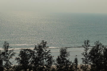 Magnificent Cox’s Bazar Bangladesh seaside landscape showing ocean horizon with clear skies and green coastal trees below.