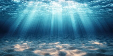 Obraz premium Sunlight rays penetrating clear blue ocean water illuminating the sandy seabed with gentle ripples