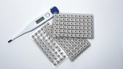 Digital thermometer with acupuncture seed patches on white background