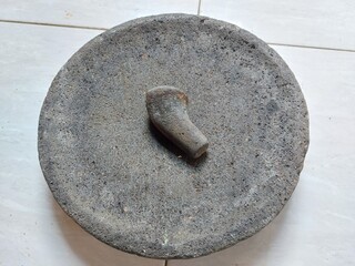 Traditional stone mortar and pestle made from volcanic rock, commonly used in Indonesian cuisine for grinding spices and herbs. Perfect for food culture, traditional cooking, and kitchen tool concepts