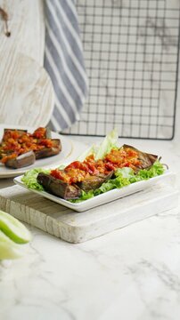 Terong Balado or eggplant with sambal balado on white background. Table setting