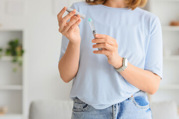 Young woman with syringe of IVF hormones at home, closeup