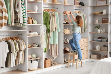 Young woman taking wicker organizer from shelf in bedroom
