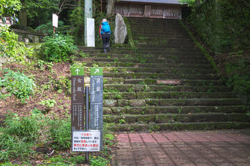 Hiker climbing stone steps on forest trail at mountain shrine entrance at Oyama mountain, Isehara,...