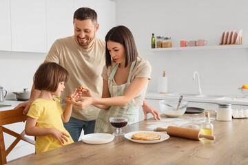Happy family eating tasty pancakes in kitchen