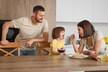 Happy family eating pancakes with jam in kitchen