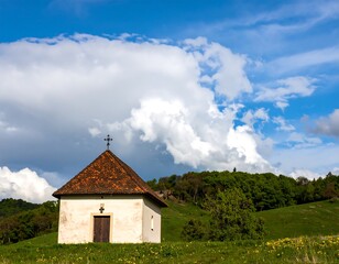 Fototapeta premium Small chapel on a grassy hill under a partly cloudy sky