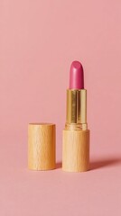 A vibrant pink lipstick with a gold casing stands upright against a soft pink background, accompanied by its matching cap.