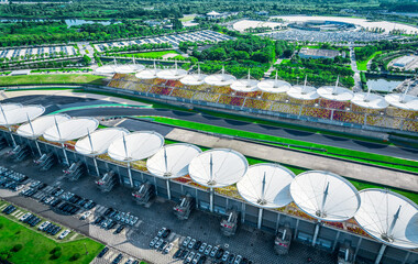 Aerial view of modern race track featuring unique circular roof architecture and colorful seats.