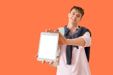 Male student with blank tablet computer on orange background