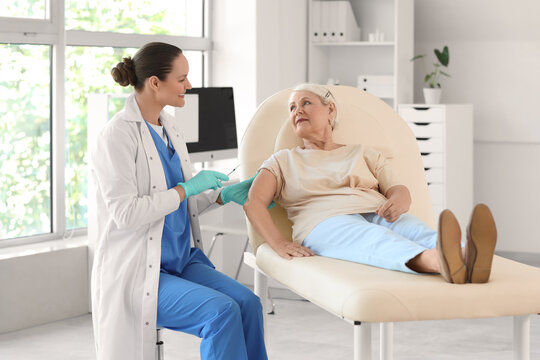 Senior woman receiving vaccine from doctor on couch in clinic