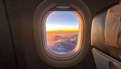 Airplane window view of sunset over clouds