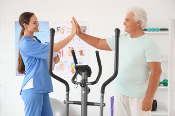 Senior man with therapist giving each other high-five in rehabilitation center