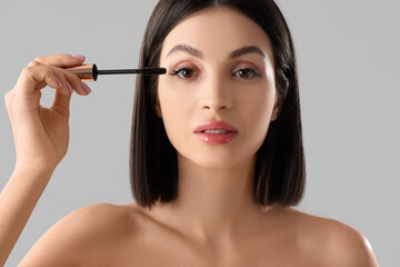 Fototapeta premium Beautiful young woman with mascara on light background, closeup