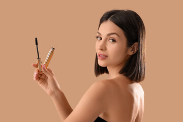 Beautiful young woman with mascara on beige background, closeup