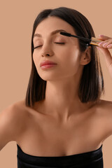 Fototapeta premium Beautiful young woman with mascara on beige background, closeup