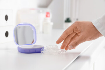 Female dentist's hand with occlusal splint on desk in office, closeup