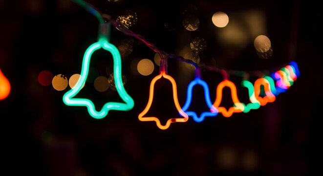 Neon bells in a festive mood glowing brightly against a dark background

