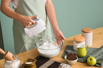 Woman whipping egg whites with mixer in kitchen