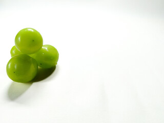 A small cluster of fresh, ripe green grapes sitting on a clean, bright white background with ample copy space for text