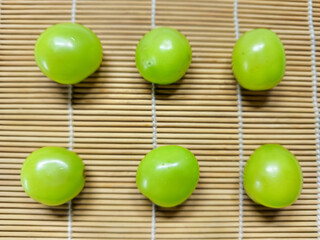 Vibrant green grapes, fresh and healthy, artfully arranged in rows on a rustic bamboo mat, perfect for a refreshing snack or delightful dessert